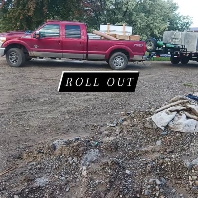 A red truck parked in the dirt next to a pile of trash.