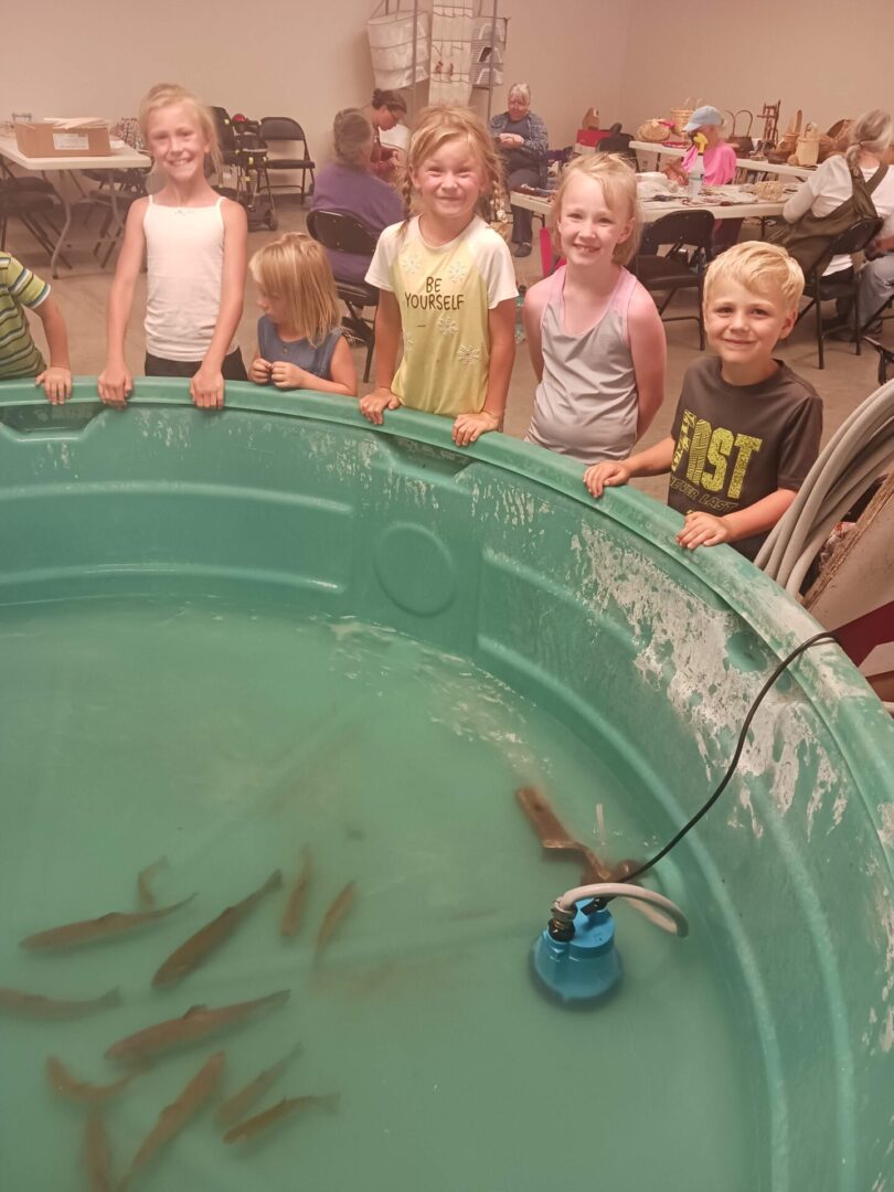 A bunch of kids watching fish in a big plastic tank.